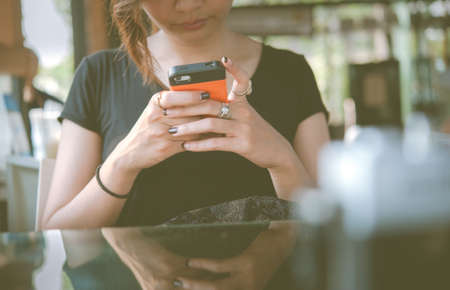 A young woman is using her smart phone , while is sitting in restaurantの写真素材