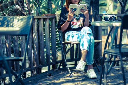 Young woman asian relax with reading a book and camera film in coffee cafe , Outdoor lifestyle&vintage tone pictureの写真素材