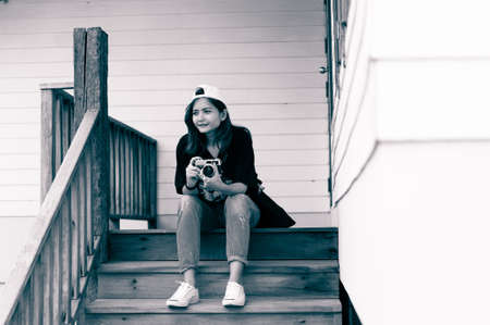 Hipster woman taking photos with retro film camera  on wooden floorof city park,beautiful girl...