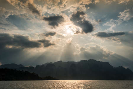 Beautiful sun rays through the clouds over mountains,evening light,Amazing scene at Khao-Sok National Park of Thailandの写真素材
