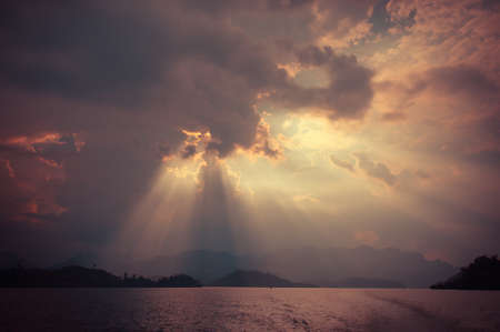 Beautiful sun rays through the clouds over mountains,evening light,Amazing scene at Khao-Sok...