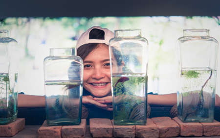 A young woman traveler watching a Fighting Fish in Bottles  at Siamese Fighting Fish Gallery ,Thailandの写真素材