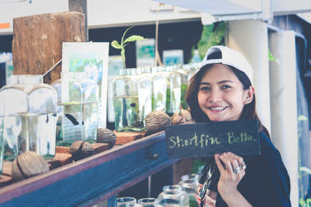 A young woman traveler watching a Fighting Fish in Bottles  at Siamese Fighting Fish Gallery ,Thailandの写真素材