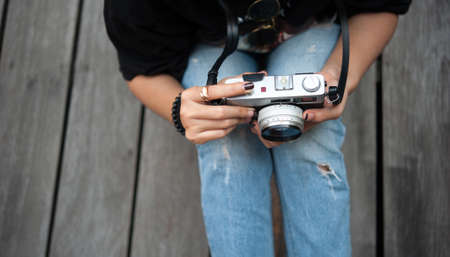 Hipster woman taking photos with retro film camera  on wooden floorof city park,beautiful girl photographed in the old cameraの写真素材