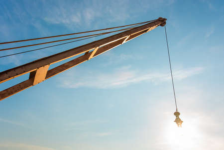 Yellow truck crane boom with hooks and scale weight above blue skyの写真素材