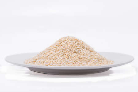 White Sesame Seeds on white plate at on white backgroundの写真素材