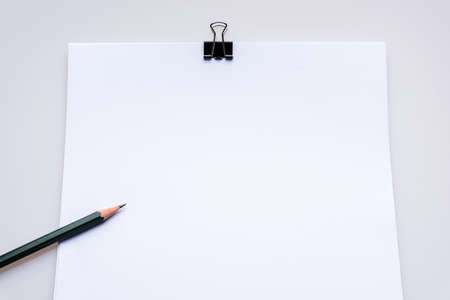 Copy space blank paper A4 and pencil and back binder clip on table white background ,top viewの写真素材