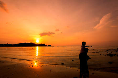 Silhouettes of father and son and sunset view on the seaの写真素材