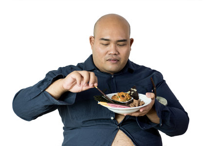 fat man eating, portrait of overweight person feels hungry and eating chips,cake,green tea frappe seated on armchai, isolated on white background with clipping pathの写真素材