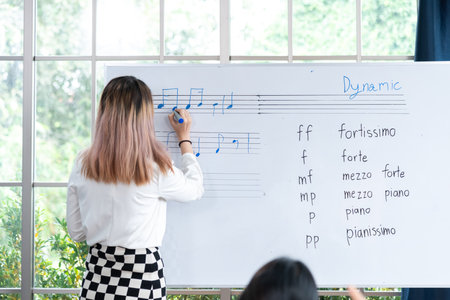 female student sitting taking notes and music teacher.の写真素材