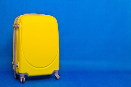 Travel bag to the wall. Yellow suitcase on a blue background.の写真素材
