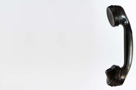 Old black telephone receiver against a white background.の写真素材