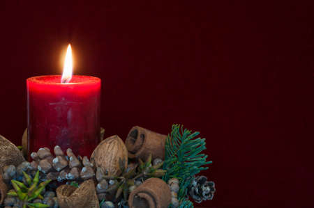Background Christmas decoration, red candle with candlelight in front of red velvet and copy space.