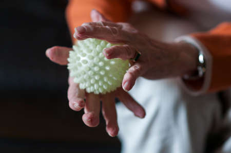Application in physiotherapy, Senior massaging her hands with a spiky ball