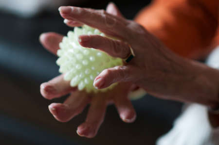 Application in physiotherapy, Senior massaging her hands with a spiky ball