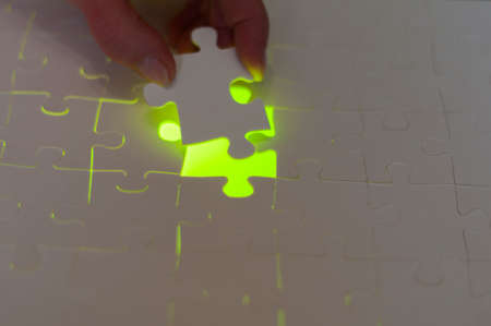 Symbol of solutions of business concepts. Hand sets last puzzle piece a with green glowing...