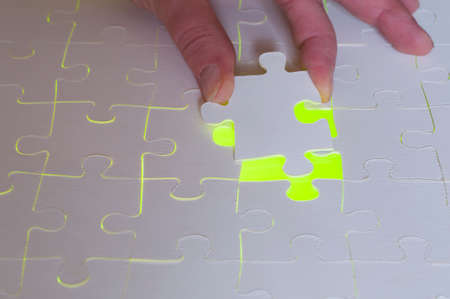 Symbol of solutions of business concepts. Hand sets last puzzle piece a with green glowing background.の写真素材