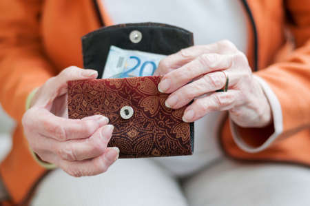 Senior women looks in her purse with Euro banknotes.の写真素材