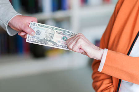 Generational conflict, old woman and young woman pulling on a dollar money bill.の写真素材