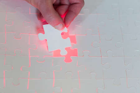 Symbol of solutions of business concepts, hand sets last puzzle piece a with red glowing background.の写真素材