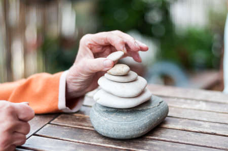 Hands of an elderly woman build a stone pyramid.の写真素材