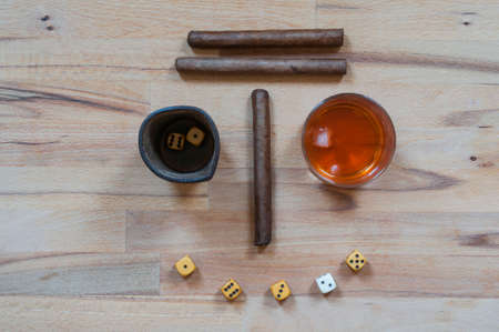 Dice game with cigars and alcoholic beverages to create a face, photographed in directly above.