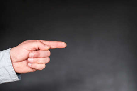 Hand with extended index finger against dark background with copy space.の写真素材