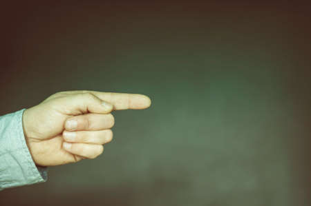 Hand with extended index finger against dark background with copy space.の写真素材