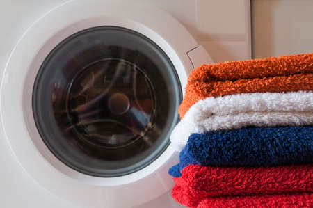 Laundry service, housework, washing machine and a stack of colorful towels.