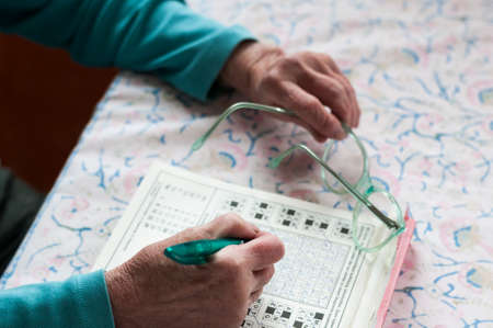 Senior women sitting at a table and solve crosswords.の写真素材
