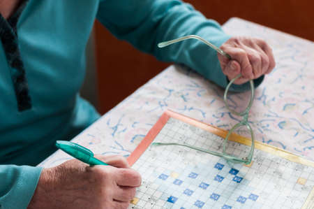 Senior women sitting at a table and solve crosswords.の写真素材
