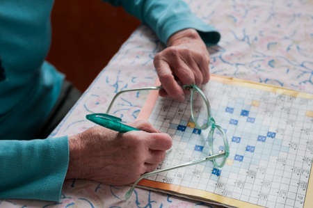 Senior women sitting at a table and solve crosswords.の写真素材