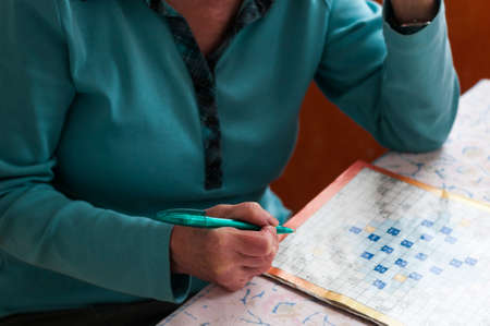 Senior women sitting at a table and solve crosswords.の写真素材