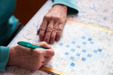 Senior women sitting at a table and solve crosswords.