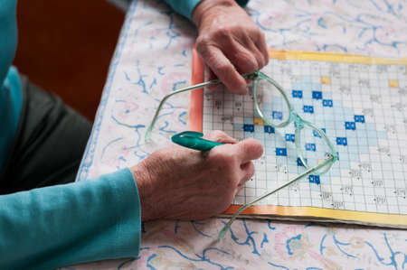 Senior women sitting at a table and solve crosswords.の写真素材