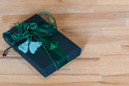 Gift in black paper with green bow in front of wood background.の写真素材