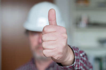 Positive emotion, construction worker showing hand with thumbs up, selective focus.の写真素材