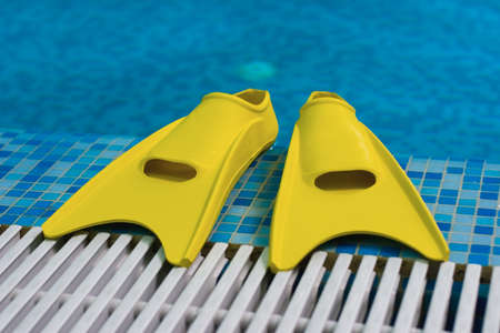 Yellow flippers on coast of swimming poolの写真素材