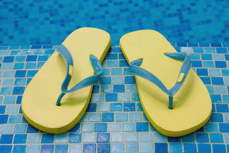 yellow sandals flipflop slippers on the blue coast of pool の写真素材