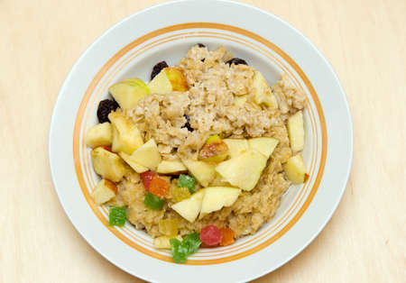Porridge with slices of apples and candied fruits in a plateの写真素材