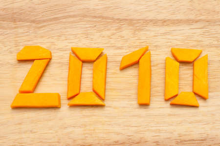 Number 2010 made of slices of a raw pumpkin on wooden backgroundの写真素材