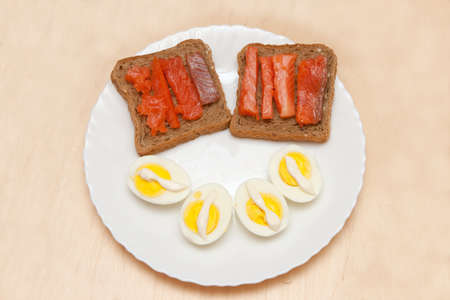 Slices of smoked salmon on bread, cut eggs with mayonnaise on plate. の写真素材