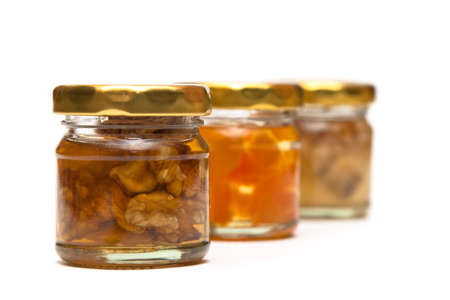 Honey with nuts in a glass jar on whiteの写真素材
