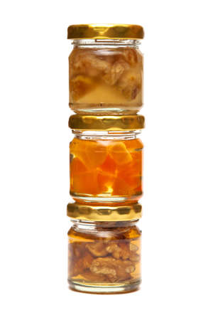 Honey with nuts in a glass jar on white in a columnの写真素材