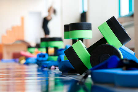 equipment for aqua aerobics on pool side. woman stretching on backgroundの写真素材
