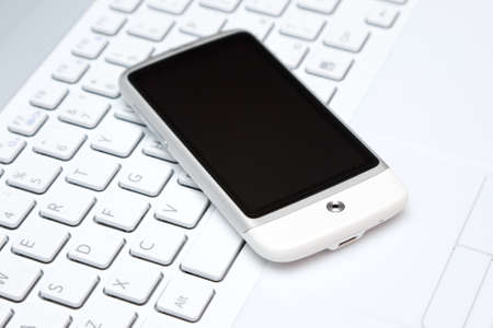 Business concept - closeup image of white touch phone over laptop
