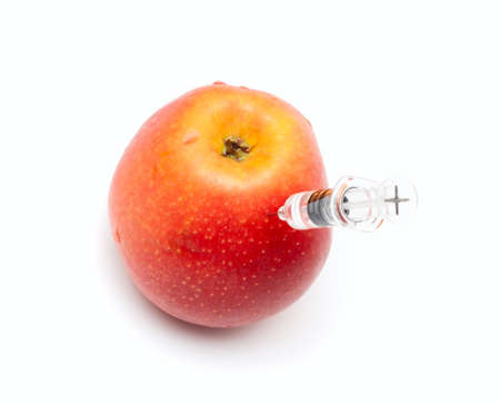 Syringe with liquid entered into red yellow apple  GMOの写真素材