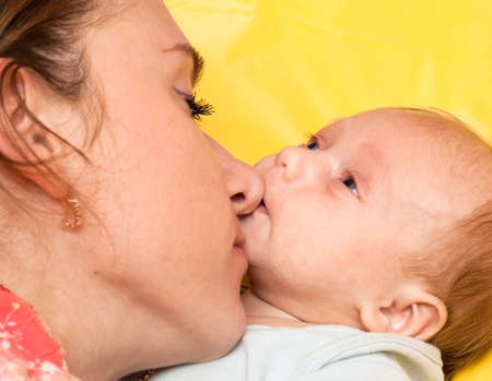 happy mother with baby on yellow backgroundの写真素材