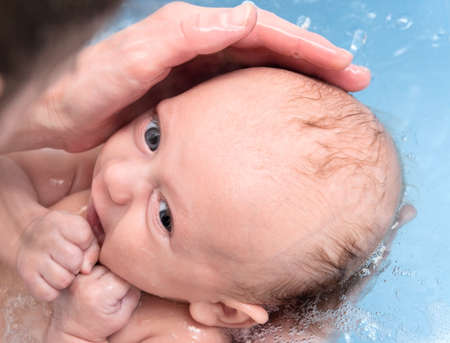 Newborn baby bathing in bathtub in handsの写真素材