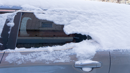 The car, covered with thick layer of snow. Negative consequence of heavy snowfalls. the left part of the car covered with snowの写真素材